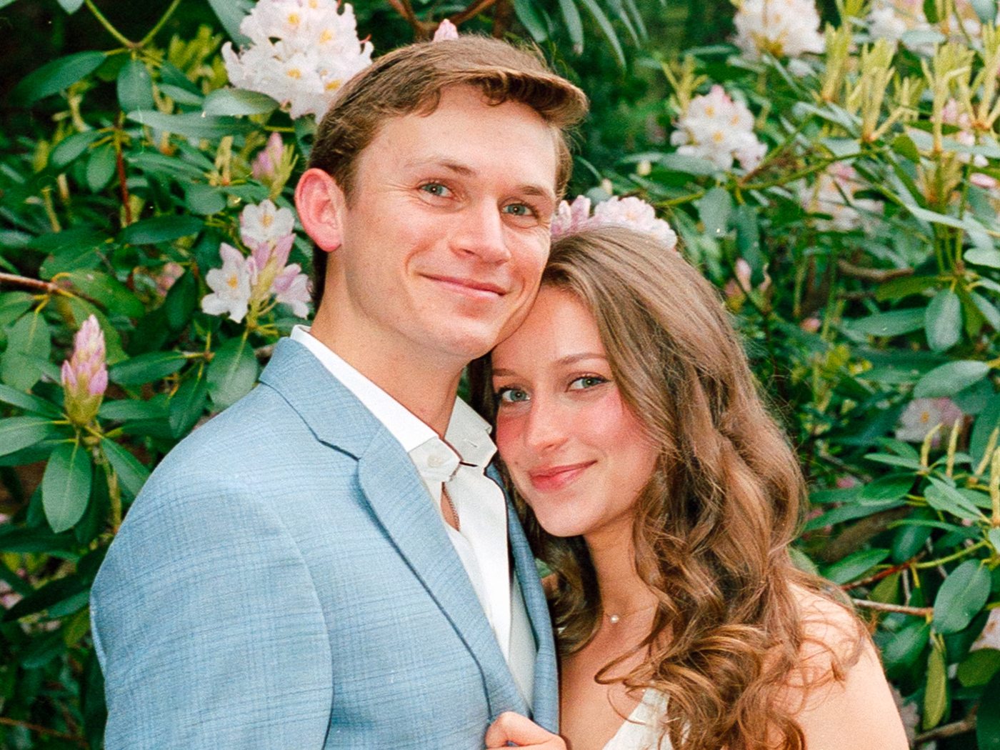 The Dalthera founders, smiling together in front of a flowering rhododendron