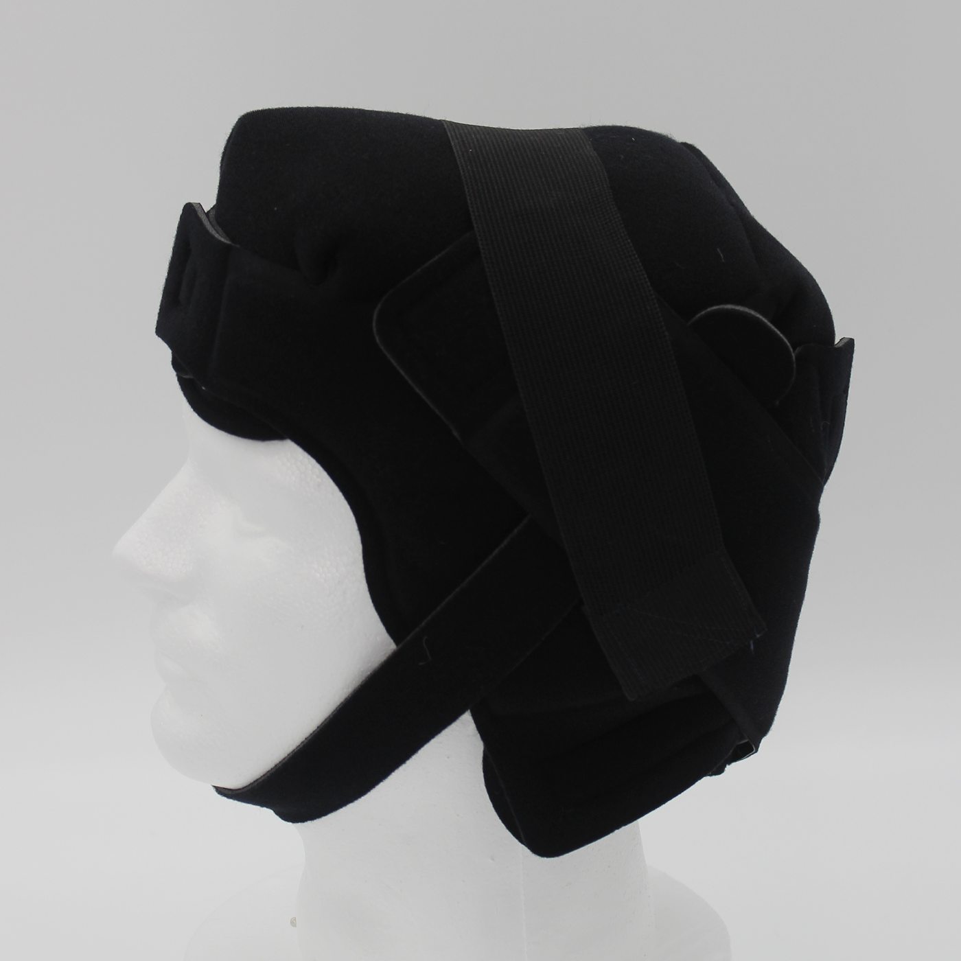 A cold cap with its chin strap on a display head, seen from the side
